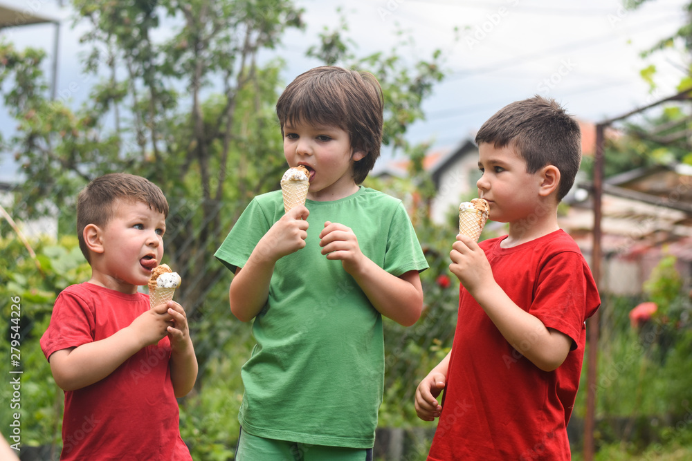 Three happy little boy eating ice cream. Closeup of children eating ice cream in the park Three happy little boy eating ice cream. Closeup of children eating ice cream in the park