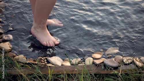 children bare feet run across the water on a summer evening, slow motion