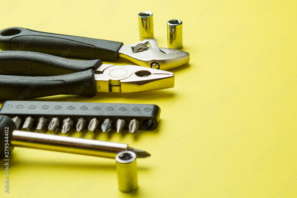 Metal tools on a yellow background, screwdriver and pliers Metal tools on a yellow background, screwdriver and pliers
