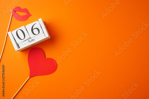 July 6, World Kiss Day, wooden calendar on an orange background, a place for an inscription, top view