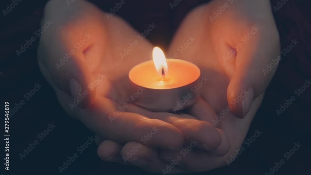 Burning candle in female hands on black background. Young woman holding burning candle in darkness. Praying with candle. Begging concept. Burning candle in female hands on black background. Young woman holding burning candle in darkness. Praying with candle. Begging concept.