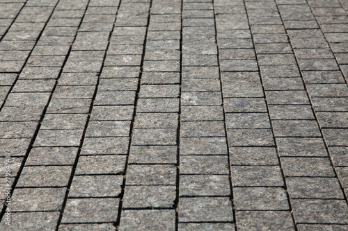Abstract background of gray cobblestone pavement,close-up in perspective.