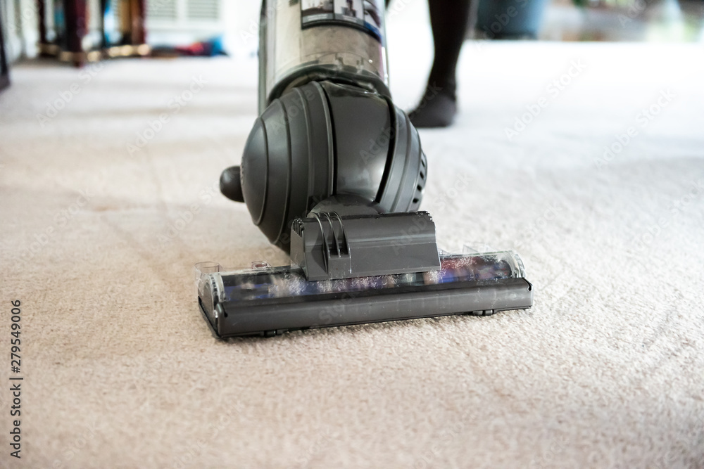 Obraz premium Closeup of woman, female doing cleaning at home with vacuum cleaner showing head, brush on carpet floor with dirt