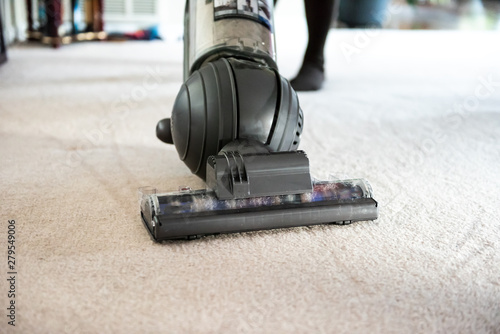 Closeup of woman, female doing cleaning at home with vacuum cleaner showing head, brush on carpet floor with dirt