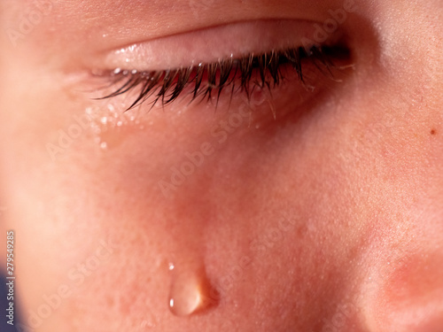 Face of crying boy close up. Eyes, eyelashes, eyebrows, lips, teeth and tears. Emotions and grimaces of upset child