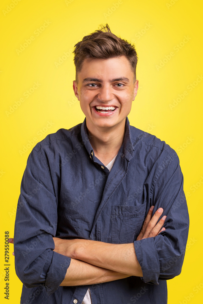 Portrait of happy young man with crossed arms standing over yellow background and looking at camera Portrait of happy young man with crossed arms standing over yellow background and looking at camera