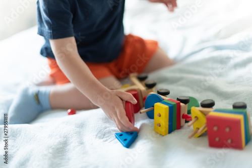 Growing up and kids leisure concept. A child playing with a colored wooden train. Kid builds constructor. Without face. Selective focus, copy space, mocup