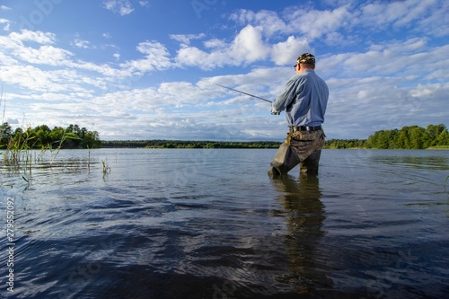 Photos angler standing in the lake and catching the fish in summer day
