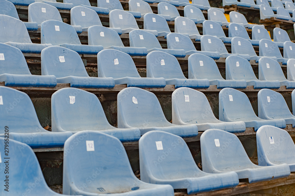 Naklejka premium Sports concept. Rows of empty grey blue plastic seats at the tribune in an open sports stadium