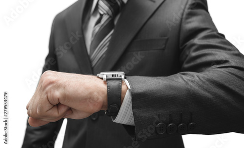 A man in a suit looks at a wrist watch.