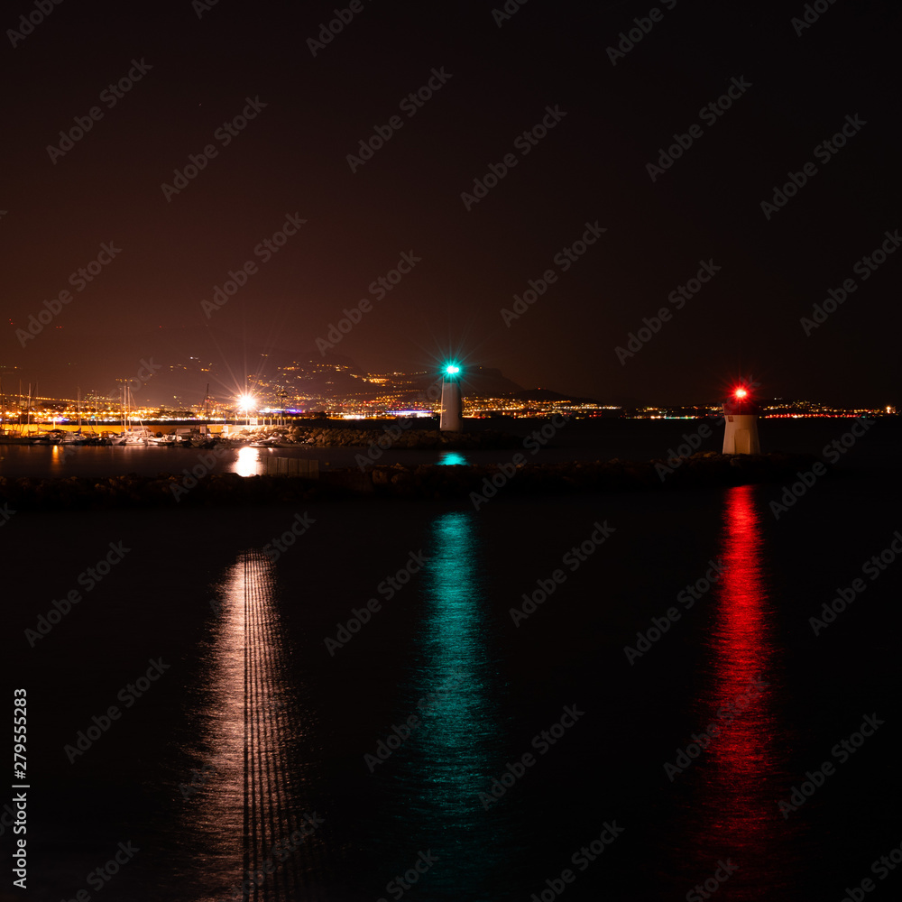 Three lighthouses with colorful lights in the Bay overlooking the city at night