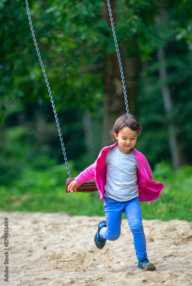 Cute little girl playing on swing in park Cute little girl playing on swing in park