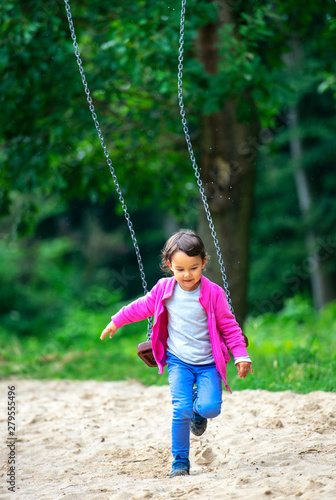 Cute little girl playing on swing in park