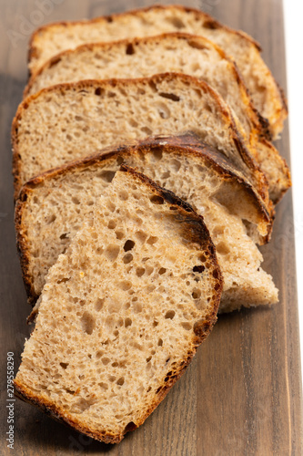 Close up of hearty artisan sourdough bread slices on a wood board.