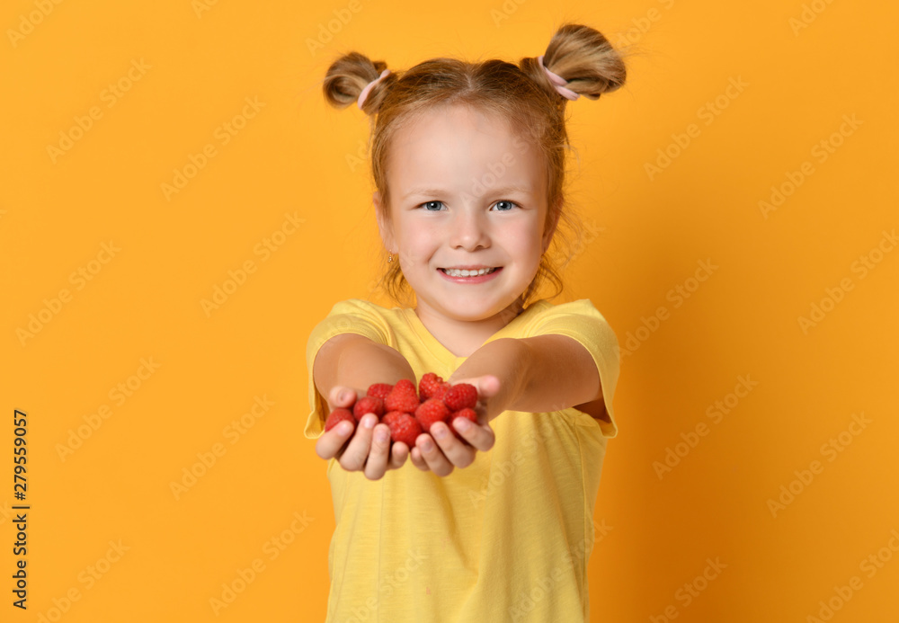 Young girl kid in blank t-shirt hold raspberries fruits in hands happy on yellow Young girl kid in blank t-shirt hold raspberries fruits in hands happy on yellow