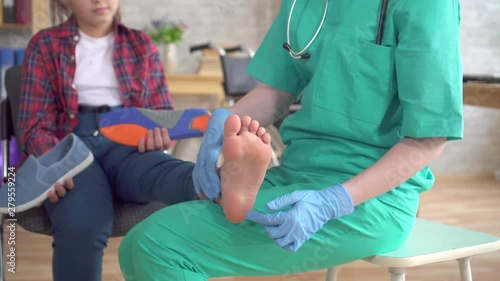 doctor kneads the foot of a teenage girl with orthopedic problems