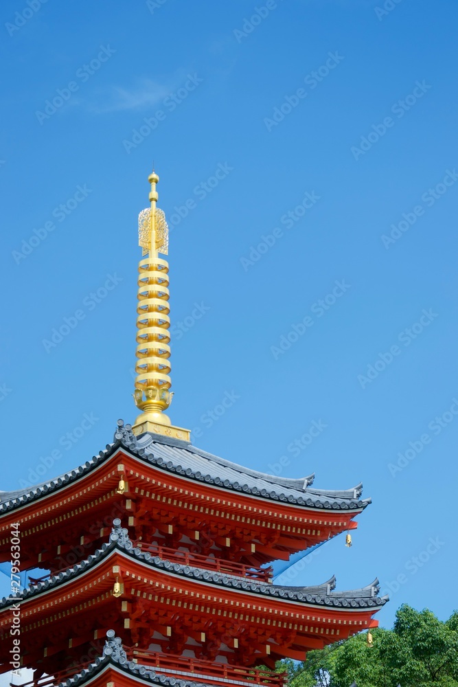 Vivid red pagoda in Fukuoka, Japan. Glowing golden spire and green trees Vivid red pagoda in Fukuoka, Japan. Glowing golden spire and green trees