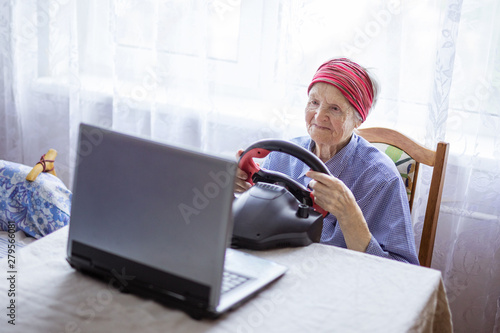 Senior woman enjoying car racing video game on laptop at home © Andrey Bandurenko