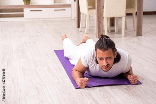 Young man doing physical exercises at home