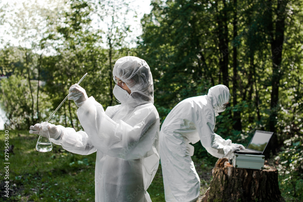 Ecological problem. Pollution. Examine soil. Scientist in protective mask and suit taking water samples from river. Chemist makes an analysis of the environment for radiation. Saving planet earth. .. Ecological problem. Pollution. Examine soil. Scientist in protective mask and suit taking water samples from river. Chemist makes an analysis of the environment for radiation. Saving planet earth. ..