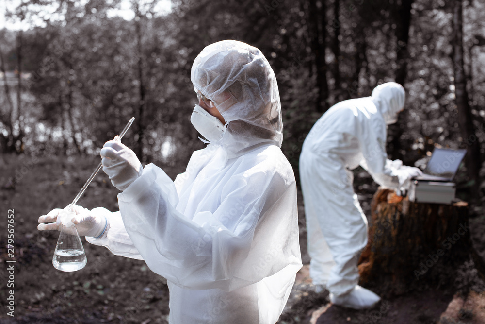 Ecological problem. Pollution. Examine soil. Scientist in protective mask and suit taking water samples from river. Chemist makes an analysis of the environment for radiation. Saving planet earth. .. Ecological problem. Pollution. Examine soil. Scientist in protective mask and suit taking water samples from river. Chemist makes an analysis of the environment for radiation. Saving planet earth. ..