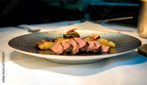 Meal on a grey plate made of meat cooked and hash browns in a high end restaurant photo