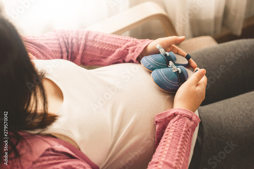 Billede på lærred Pregnant woman feeling happy at home while taking care of her child