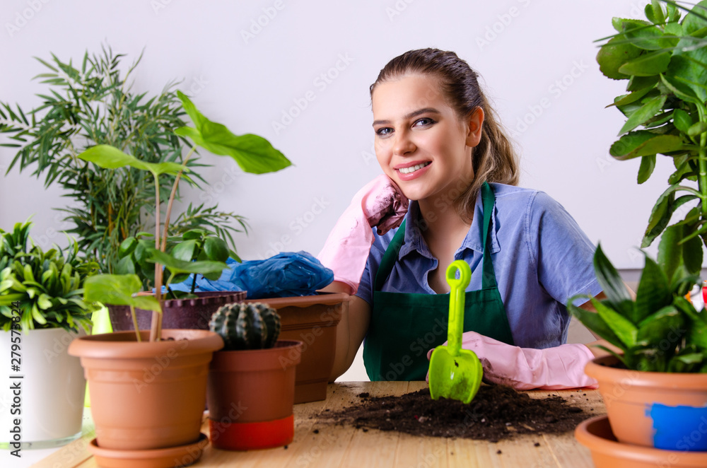 Young female gardener with plants indoors Young female gardener with plants indoors