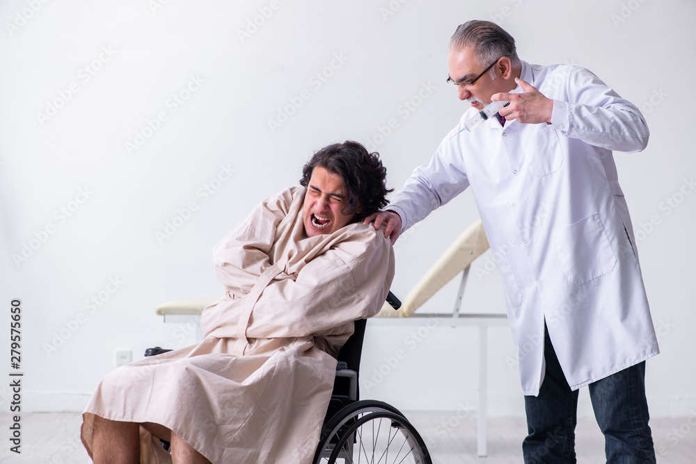 Obraz premium Old male doctor psychiatrist and patient in wheel-chair