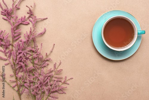 Cup of hot tea and a tamarix gallica tree branches on a brown background.