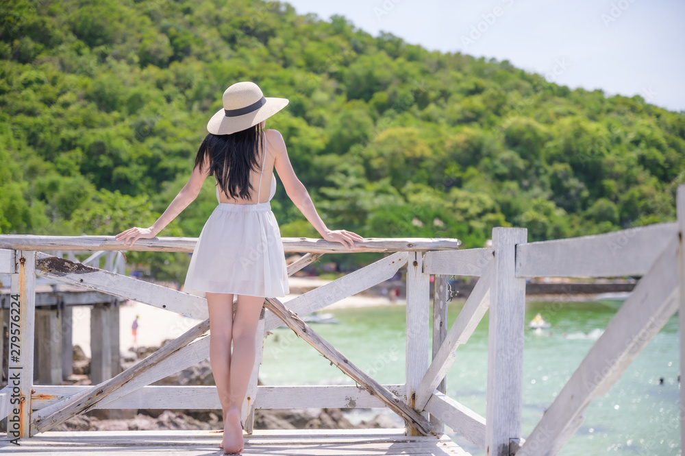 young woman standing on wooden bridge, enjoy the sea beach in summer vacation and long holidays, tourist in island travel