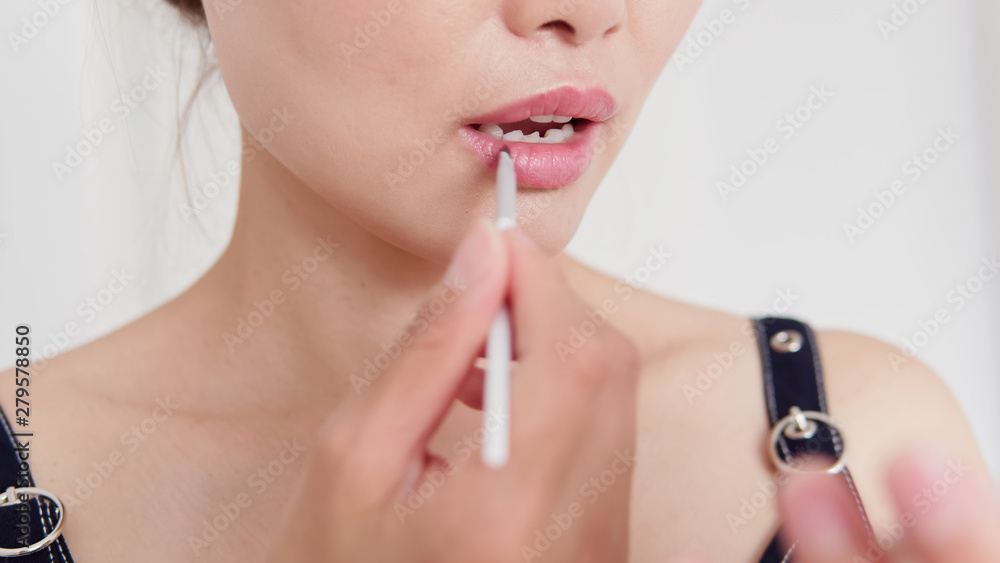 Woman is painting lips with lip gloss. Female making self makeup with brushes, Super close-up, lip makeup, beauty concept.