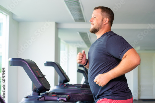 full male runs on a treadmill in a gym. concept of weight loss and sport. side view.
