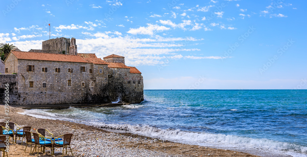 Panorama of Budva Old Town Citadel and Adriatic Sea with an outdoor cafe on Richard s Head beach in Montenegro, Balkans