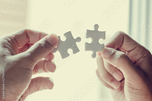 Closeup hand of woman connecting jigsaw puzzle with sunlight effect, Business solutions, success and strategy concept