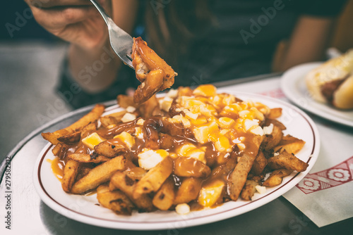 Poutine french fries canadian local classic dish in the province of Quebec, Canada. Fast food retro diner restaurant serving plate of fried potates with brown gravy sauce and fresh cheese curds. photo
