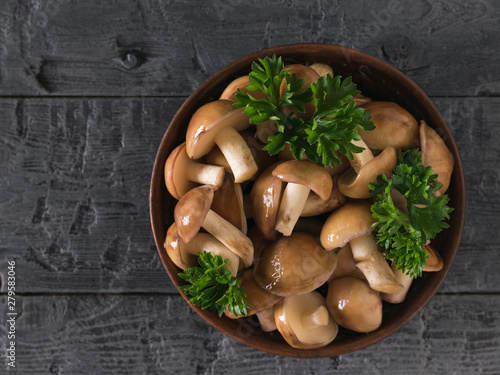 Mushrooms in a clay bowl and on a rustic wooden table. The view from the top.