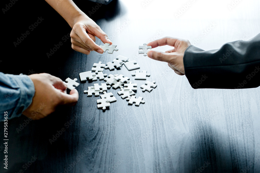 Closeup of businessman and woman with jigsaw puzzle pieces in office Closeup of businessman and woman with jigsaw puzzle pieces in office