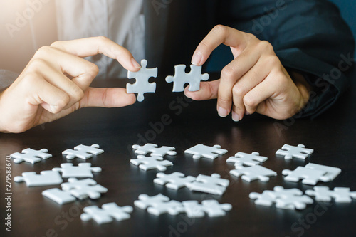 Closeup of businessman and woman with jigsaw puzzle pieces in office
