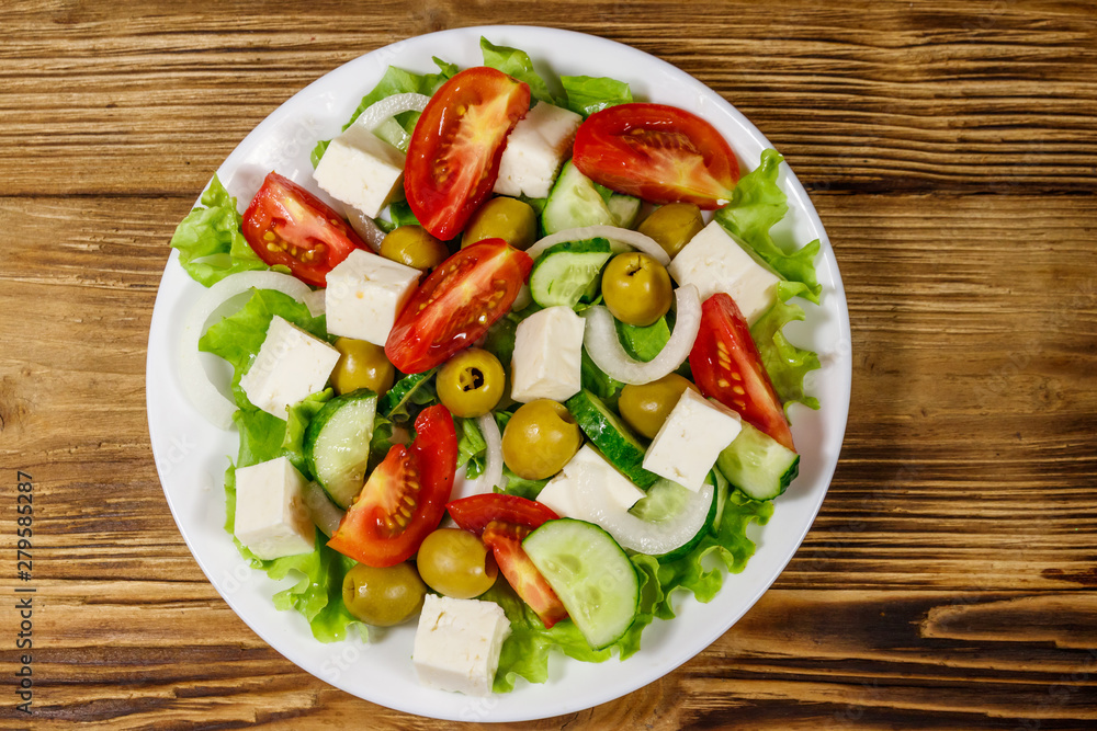 Greek salad with fresh vegetables, feta cheese and green olives on wooden table. Top view Greek salad with fresh vegetables, feta cheese and green olives on wooden table. Top view