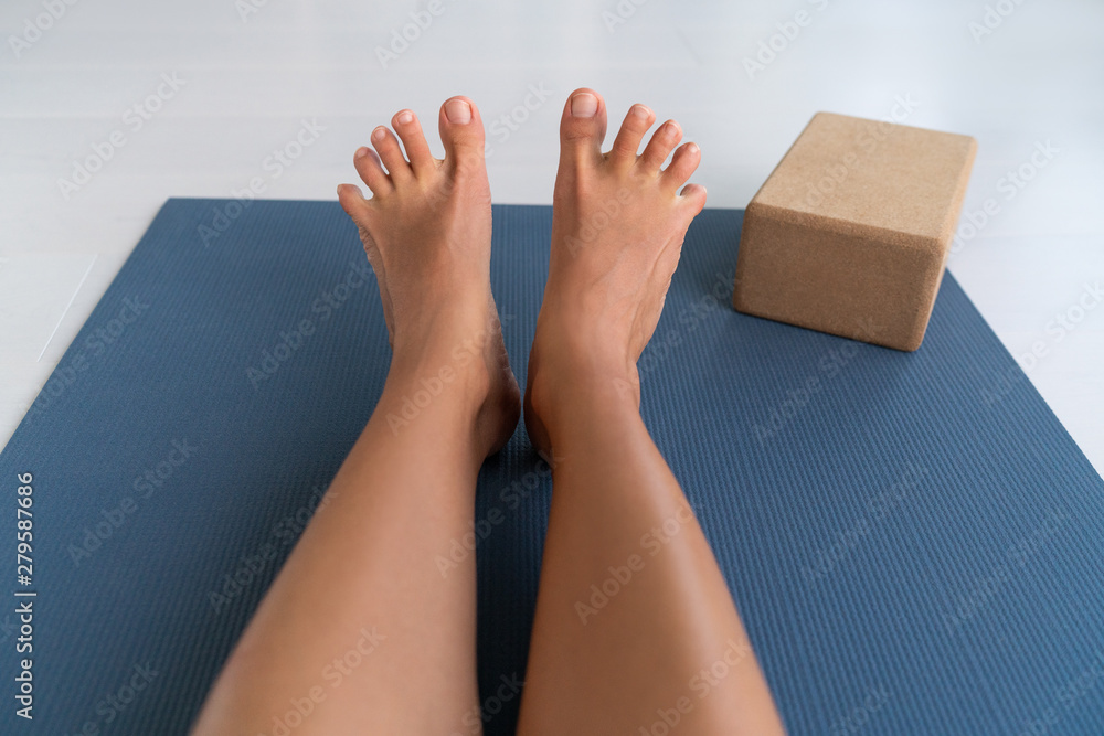 Yoga woman stretching feet spreading her toes doing toe stretch on exercise  mat of living room floor at home. Foot exercises stretches fun. Stock Photo