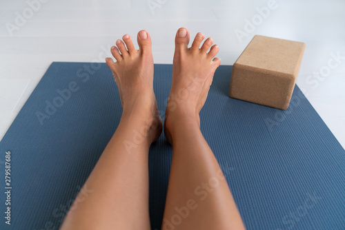 Yoga woman stretching feet spreading her toes doing toe stretch on exercise mat of living room floor at home. Foot exercises stretches fun.