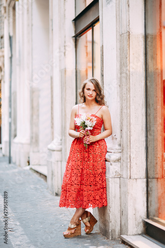 Portrait of a girl in a red dress and hat. Stylish bride on the streets of Rome.