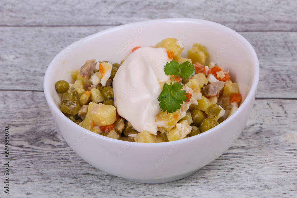 Traditional Russian salad with chicken in the white bowl Traditional Russian salad with chicken in the white bowl