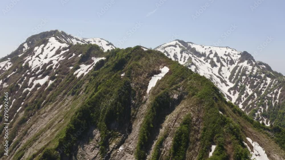 Japanese Alps summit, Niigata. Greenery & snow capped peaks aerial view over stunning landscape. Japanese Alps summit, Niigata. Greenery & snow capped peaks aerial view over stunning landscape.