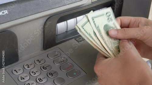This close up video shows anonymous hands taking withdrawn money out of ATM machine and counting it.