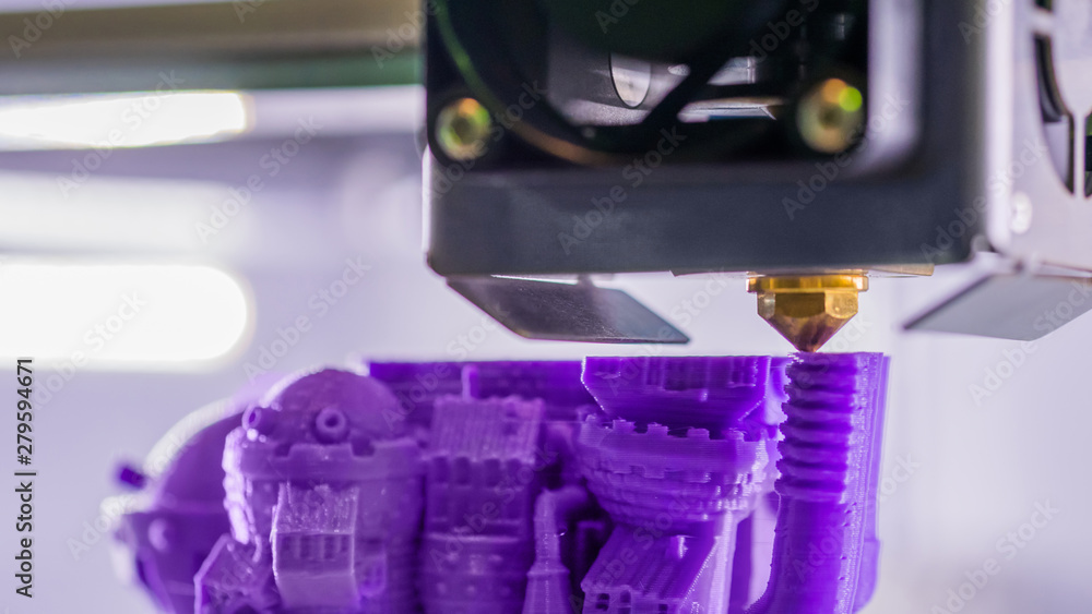 Close up shot - 3D printer prints physical 3D model of purple toy castle with plastic wire filament at modern technology exhibition. Additive technologies, science and futuristic concept Close up shot - 3D printer prints physical 3D model of purple toy castle with plastic wire filament at modern technology exhibition. Additive technologies, science and futuristic concept