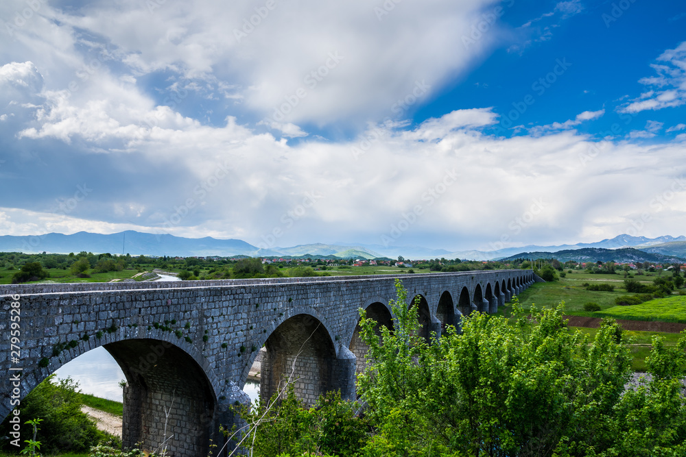 Montenegro, Impressive old bridge building called emperors bridge over zeta river in niksic village surrounded by endless green nature landscape and mountains