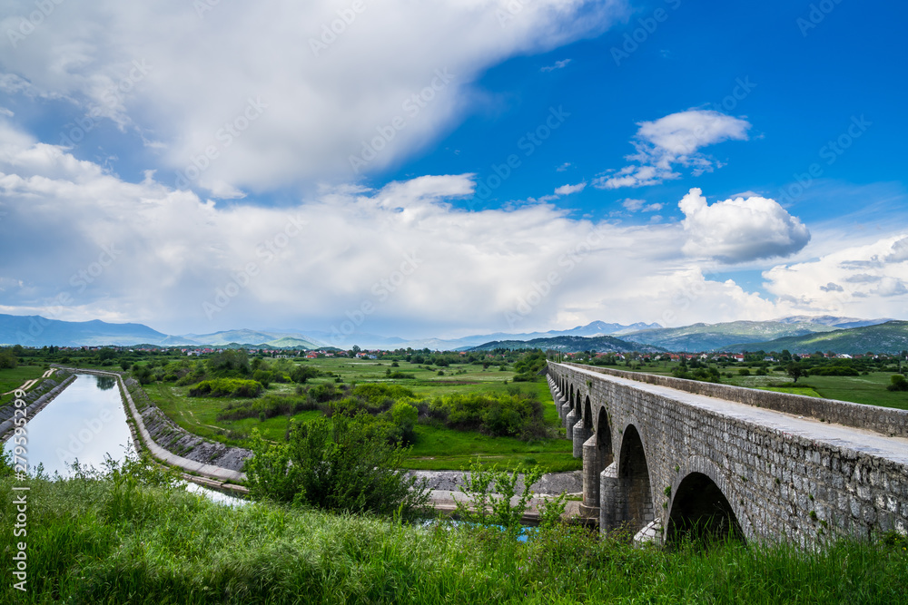 Fototapeta premium Montenegro, Ancient bridge emperors bridge building over zeta river water in niksic town surrounded by mountains in green nature landscape