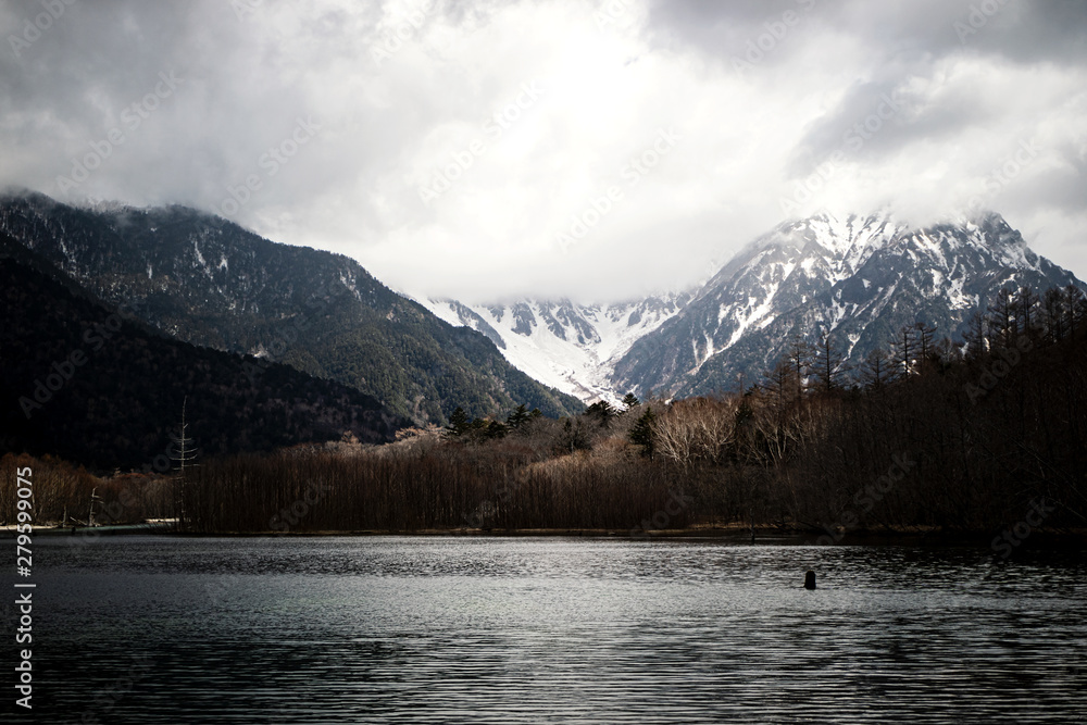 Landscape view low light tone with snow covered mountains and forest in late winter at Kamikochi, Japan National Park, Nagano